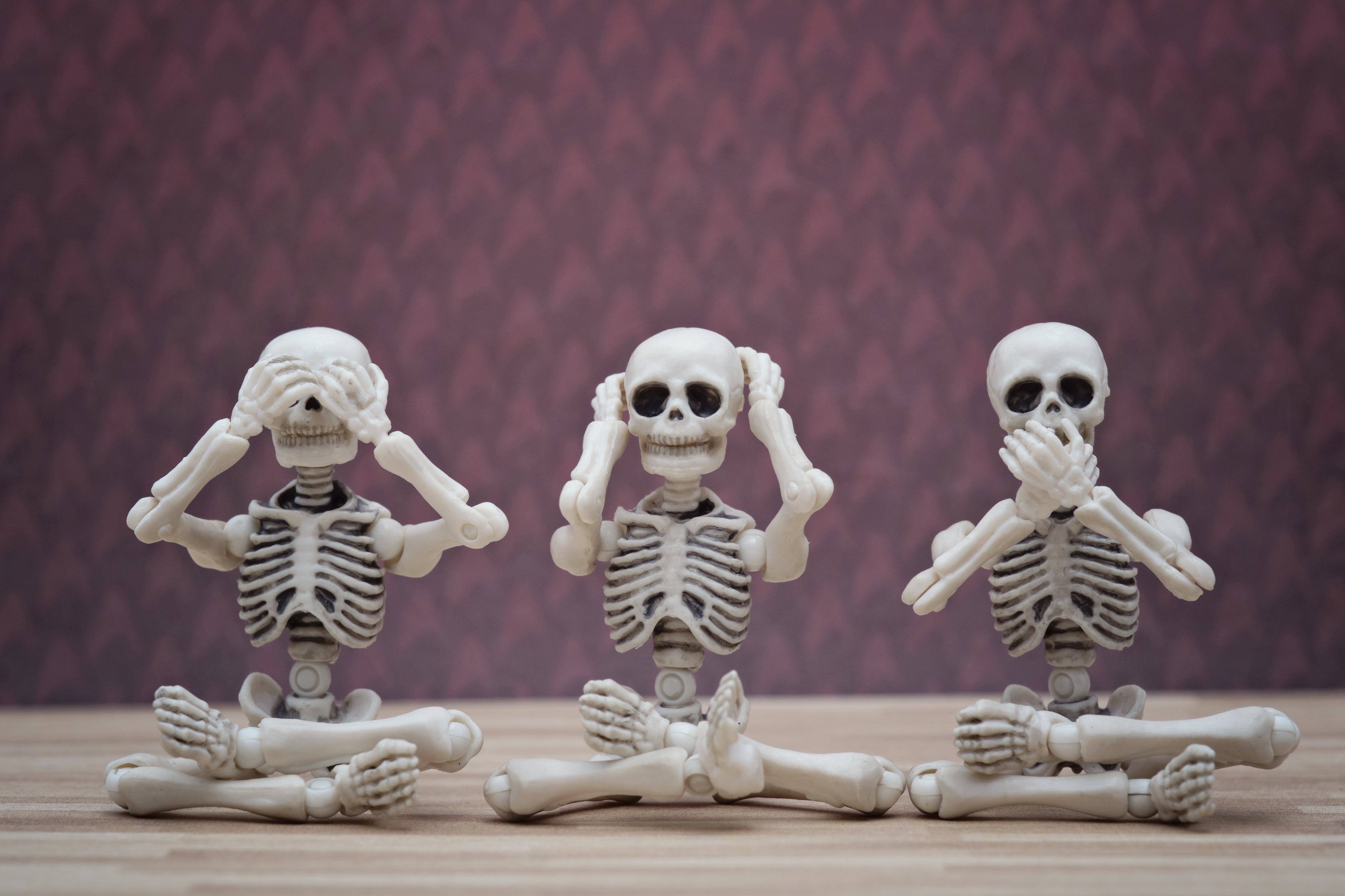 Three skeletons covering eyes, ears, and mouth