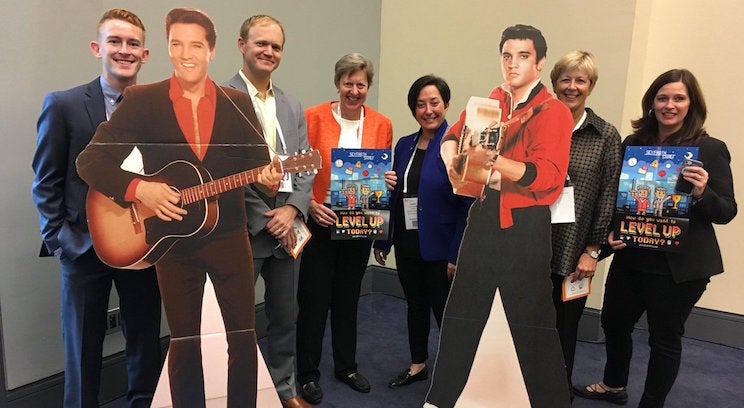a photo of 6 people standing with 2 elvis cardboard figures