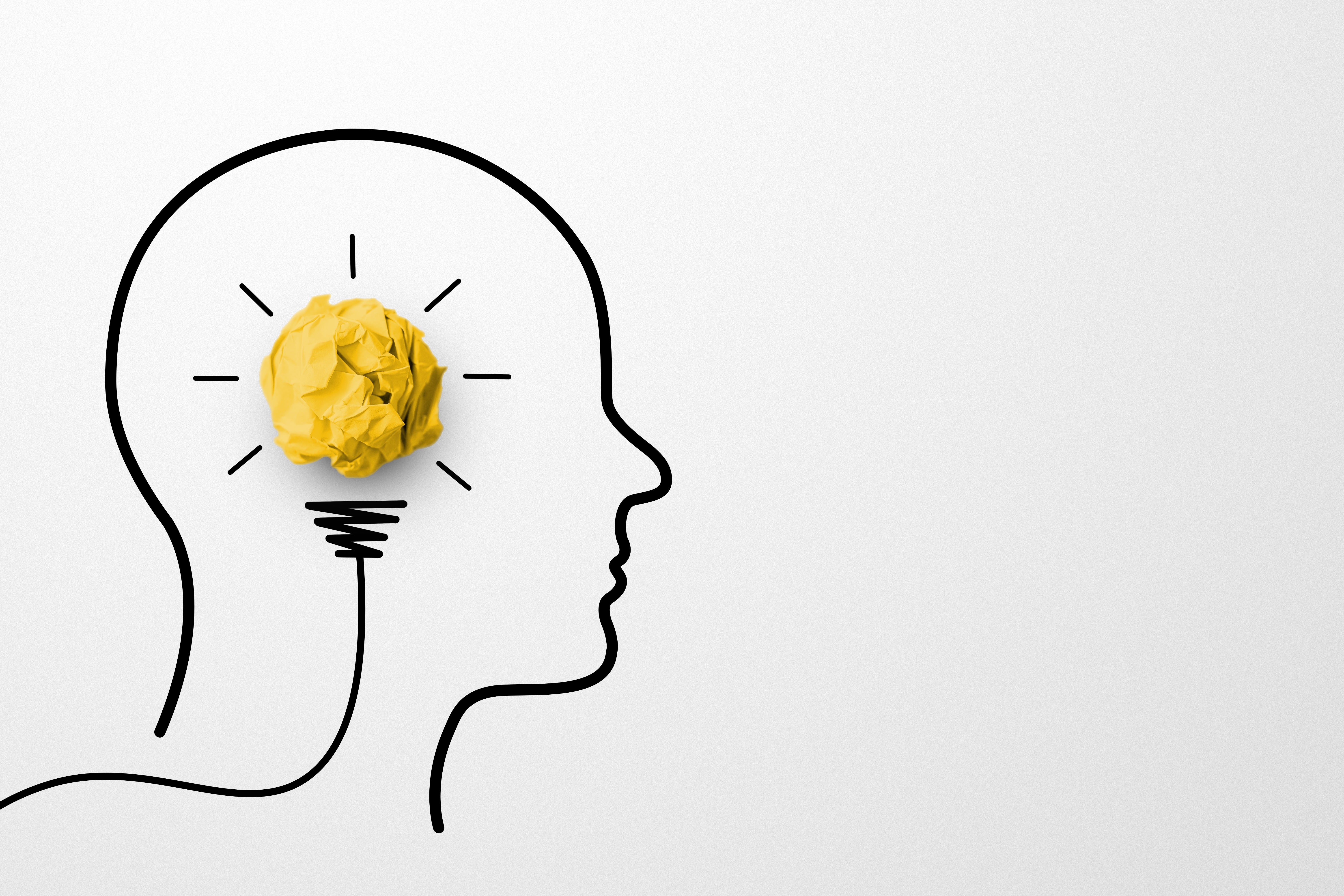 Yellow paper scrap ball resembling a light bulb inside a human drawn head. 