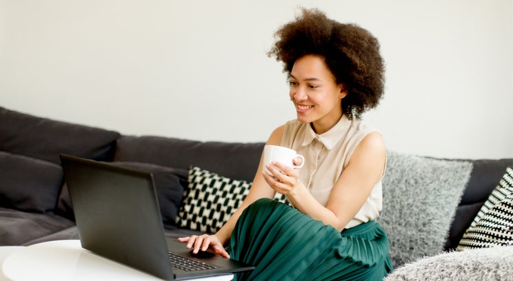 a woman sitting on her couch and using a laptop