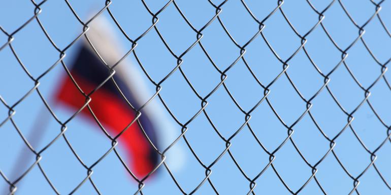 Russia flag behind chain link fence