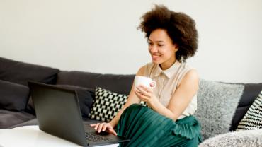 a woman sitting on her couch and using a laptop
