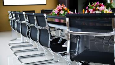 business chairs placed around a table with flowers on top