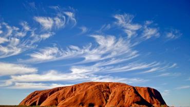 uluru rock with blue sky and wispy clouds
