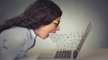 photo of woman, white skin, mouth open at laptop with letters coming out as though pouring out comments -- looks somewhat angry, frustrated,