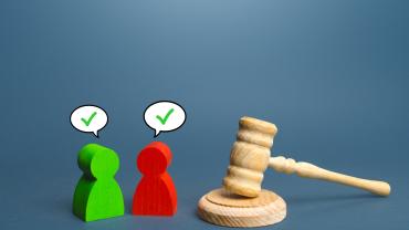 2 wooden-like figures, 1 red, 1 green, with checkmarks over heads, next to gavel