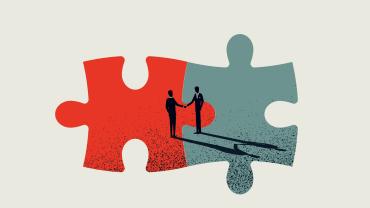 Two individuals shaking hands in agreement with two conjoined puzzle pieces as the backdrop. 