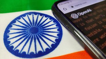 Indian flag with phone laying on top of it. Phone has OpenAI imaging. 