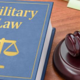 military law book and judge's gavel on a wooden desk