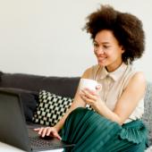 a woman sitting on her couch and using a laptop