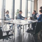 five professionals seated at a table in a meeting