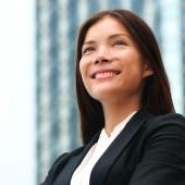 woman in a suit smiling with a faded image of a building in the background