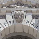 stone façade archway with a Greek face between "city" and "hall"
