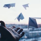 a hand lets go of four paper airplanes