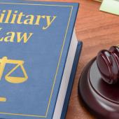 military law book and judge's gavel on a wooden desk
