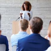 a young woman standing at a podium in front of an audience