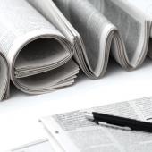 multiple newspapers and a pen on a table