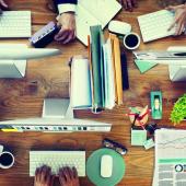 top view of a desk with four users working on computers and papers organized next to them