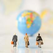Figures of businesspeople walking toward a globe.
