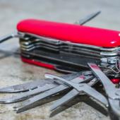 Red Swiss Army Knife that's unfolded on a stone counter