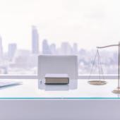 table with laptops, book, scales of justice, city skyline through window, half-tone