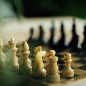 Black and white chess pieces facing each other on chess board. 