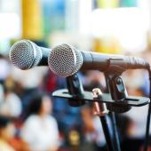Double microphone in front of a blurred out crowd of people. 