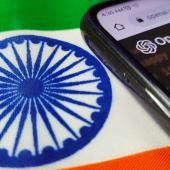 Indian flag with phone laying on top of it. Phone has OpenAI imaging. 
