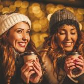 two women wearing winter clothes and holding hot beverages