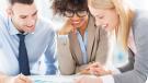 three professionals leaning on a table reviewing papers